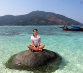 Nina Fordham perched on a rock with Ko Adang and catamaran Nina behind
